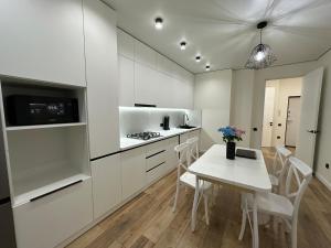 una cucina con mobili bianchi, tavolo e sedie di Двухкомнатной квартиры с раздельными спальнями центре Атырау ЖК Ayagoz a Atyraū