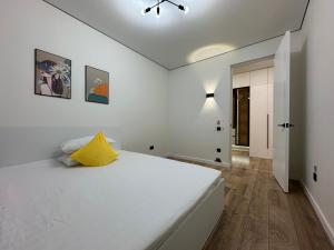 una camera bianca con un grande letto con un cuscino giallo di Двухкомнатной квартиры с раздельными спальнями центре Атырау ЖК Ayagoz a Atyraū