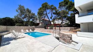 a swimming pool with lounge chairs next to a house at Villa Charisma Gajac in Novalja