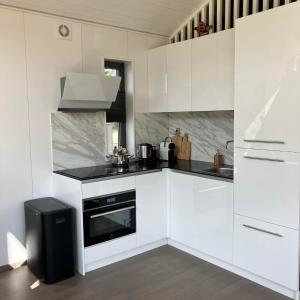 Una cocina blanca con estufa y fregadero. en Bungalow Lupine | 4 personen - Vakantiepark De Kremmer, en Gasselte