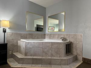 a large bathroom with a tub and two mirrors at Baymont by Wyndham Louisville Airport South in Louisville +21 photos