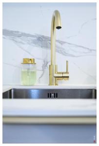 eine Küchenspüle mit einem goldenen Wasserhahn in der Unterkunft Entre Paris et le Chateau de Versailles - Parking in Rueil-Malmaison