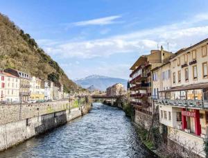 a river flowing through a city with buildings at Auberge Le LEO de FOIX in Foix