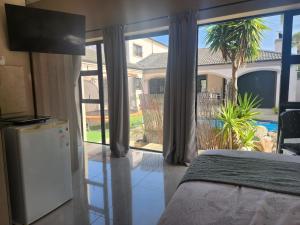 a bedroom with a bed and a sliding glass door at Balmoral Cottage, West Beach in Cape Town