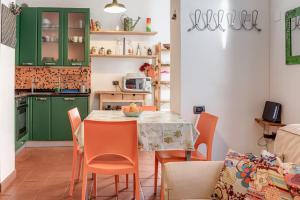 a kitchen with green cabinets and a table with orange chairs at Garden House Firenze - Careggi Meyer - Tramvia - 10 min dal Centro - Parcheggio vicinanze in Florence