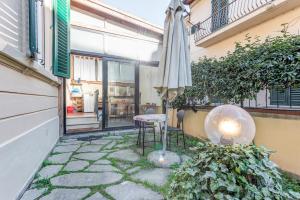 Un patio con una sombrilla y una mesa y sillas. en Garden House - Sweet Dreams in Florence, en Florencia