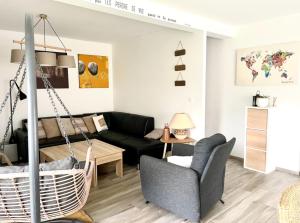 a living room with a black couch and a swing at MAISON AVEC PISCINE BERGHEIM Village préféré des Français in Bergheim