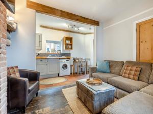 a living room with a couch and a kitchen at Melrose Cottage in Cromer