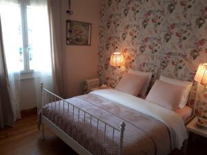 una camera da letto con un letto con carta da parati floreale e 2 lampade di Mostarlic Vegan and Gluten free B&B a Bouconville