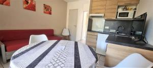 a room with a bed and a kitchen with a microwave at Les pieds dans l'eau ! in Cerbère