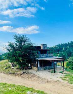a house on top of a hill with a tree at Medio Cielo Cabaña de Montaña in Rincón de Luna