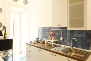 ナポリにあるNanà Bed and Breakfastの白いキャビネットとシンクのあるキッチン +105枚の写真