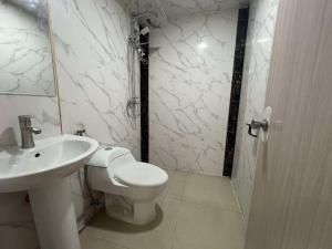 Un baño blanco con inodoro y lavabo. en Maine City Residences Tramo, en Manila 23 fotos más