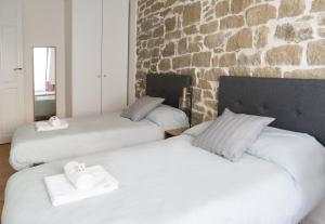 two beds in a room with a stone wall at Entre Algodones in Logroño