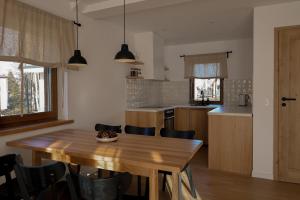 a kitchen with a wooden table and some chairs at Leśne Chatki - domek Jodła in Koniaków