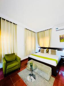 una camera con un grande letto e una sedia verde di The Tranquil Mews ad Abuja