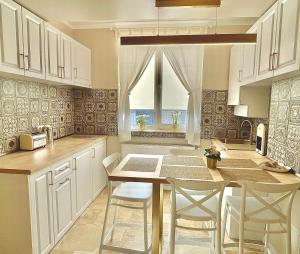 a kitchen with white cabinets and a table and chairs at Apartament Alexandru Saturn in Saturn