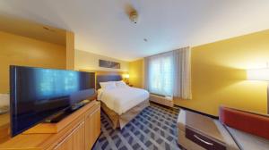 a hotel room with a bed and a flat screen tv at Residences at Tewksbury in Tewksbury
