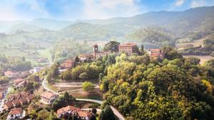 a small town on a hill with houses and trees at Castello di Casalborgone, Luxury Italian Castle Hotel in Casalborgone