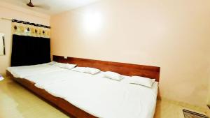a bedroom with a bed with white sheets and pillows at Vidya home stay- 500 mt from Mahakal lok and railway station in Ujjain