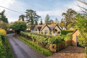 a house with a fence next to a street at Badgemore Cottage in Henley on Thames