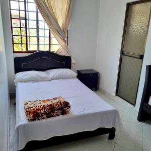 a bedroom with a bed with white sheets and a window at Hotel Iloa in Pitalito