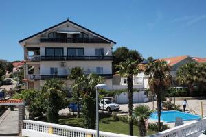 a house with a swimming pool and palm trees at Apartments Božena in Vodice