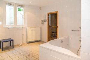 a large white bathroom with a tub and a window at Seebad Ahlbeck - Haus MIRAMAR in Heringsdorf +3 photos