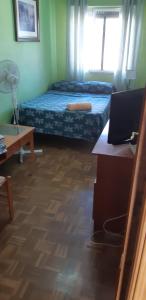 a bedroom with a bed and a desk with a laptop at Habitación LCV in Madrid