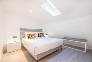 a white bedroom with a bed and a skylight at Old Town Charm Apartment in Albufeira