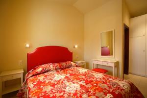 a bedroom with a red bed and a red headboard at Porto Skopelos Villas in Skopelos Town