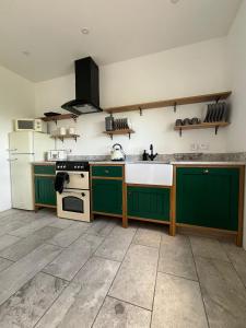 a kitchen with green cabinets and a white refrigerator at Andy's Cottages at the Well in Hilltown +29 photos