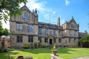 an old stone house with a green lawn in front of it at Bagshaw Hall in Bakewell