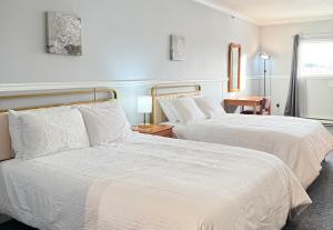 ホワイトホースにあるElite Hotel -Downtown Center- "Ski & Northern light Tour" "Hot Spring Tour "Long-term stay"の白いシーツが敷かれたホテルの部屋にベッドが2つある