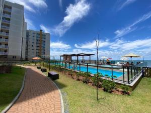 a pool with benches and umbrellas next to a building at Apto Brilho do Sol - Barra Velha - SC in Barra Velha