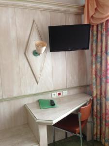 a room with a desk with a television on a wall at Hotel Union in Sarreguemines
