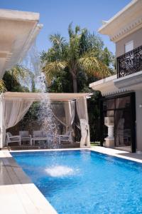 a swimming pool with a fountain in front of a house at Villa Inna in Caesarea +12 photos