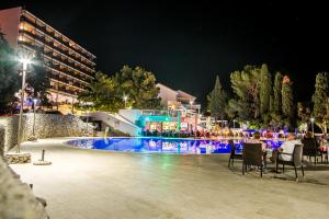 a swimming pool at night with people sitting around it at Hotel Dražica - Hotel Resort Dražica in Krk