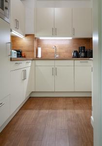 a kitchen with white cabinets and a wooden floor at F35B 18 Seaside 18 in Westerland (Sylt) +11 photos