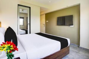 a bedroom with a white bed with a tv on the wall at Hotel O Siba Inn in Mumbai +25 photos