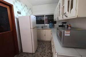 a kitchen with a white refrigerator and white cabinets at Encasa - Palm 206 in Poza Rica de Hidalgo