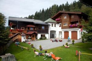 a group of people sitting in the yard of a house at Berggasthof-Ferienbauernhof Habersatt in Altenmarkt im Pongau
