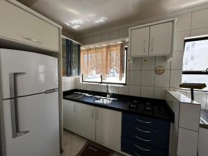 a kitchen with a white refrigerator and a sink at APT ALUGUEL Praia central in Balneário Camboriú