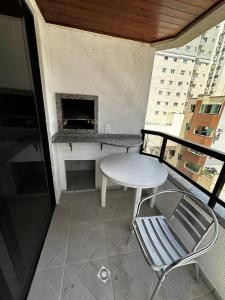 a balcony with a table and chairs and a fireplace at APT ALUGUEL Praia central in Balneário Camboriú