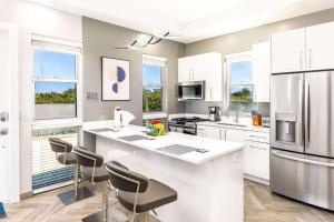 a kitchen with white cabinets and a kitchen island with stools at Romantic Escape, Walk to Beach, Pool, Hammock in Long Bay Hills