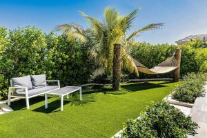 a hammock and a chair in a garden with a palm tree at Romantic Escape, Walk to Beach, Pool, Hammock in Long Bay Hills