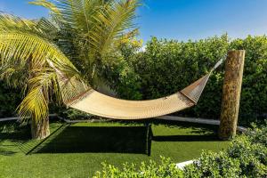 a hammock hanging from two palm trees in a garden at Romantic Escape, Walk to Beach, Pool, Hammock in Long Bay Hills