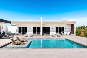 a swimming pool with chairs and a house at Romantic Escape, Walk to Beach, Pool, Hammock in Long Bay Hills