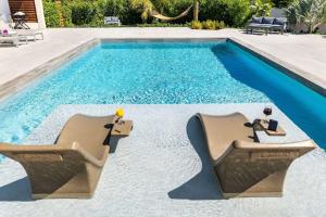 a swimming pool with two chairs next to it at Romantic Escape, Walk to Beach, Pool, Hammock in Long Bay Hills