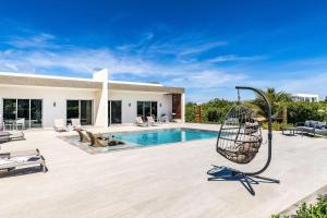 a patio with a swing next to a swimming pool at Romantic Escape, Walk to Beach, Pool, Hammock in Long Bay Hills